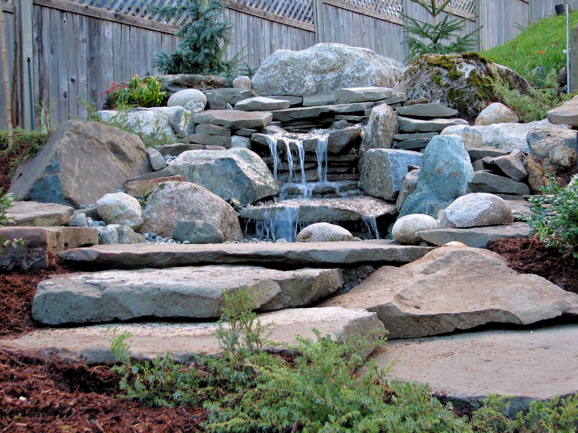 Custom hardscaping in Amesbury, MA by Pondhill Greenscapes, featuring retaining walls, decks, pergolas, and fencing for outdoor spaces